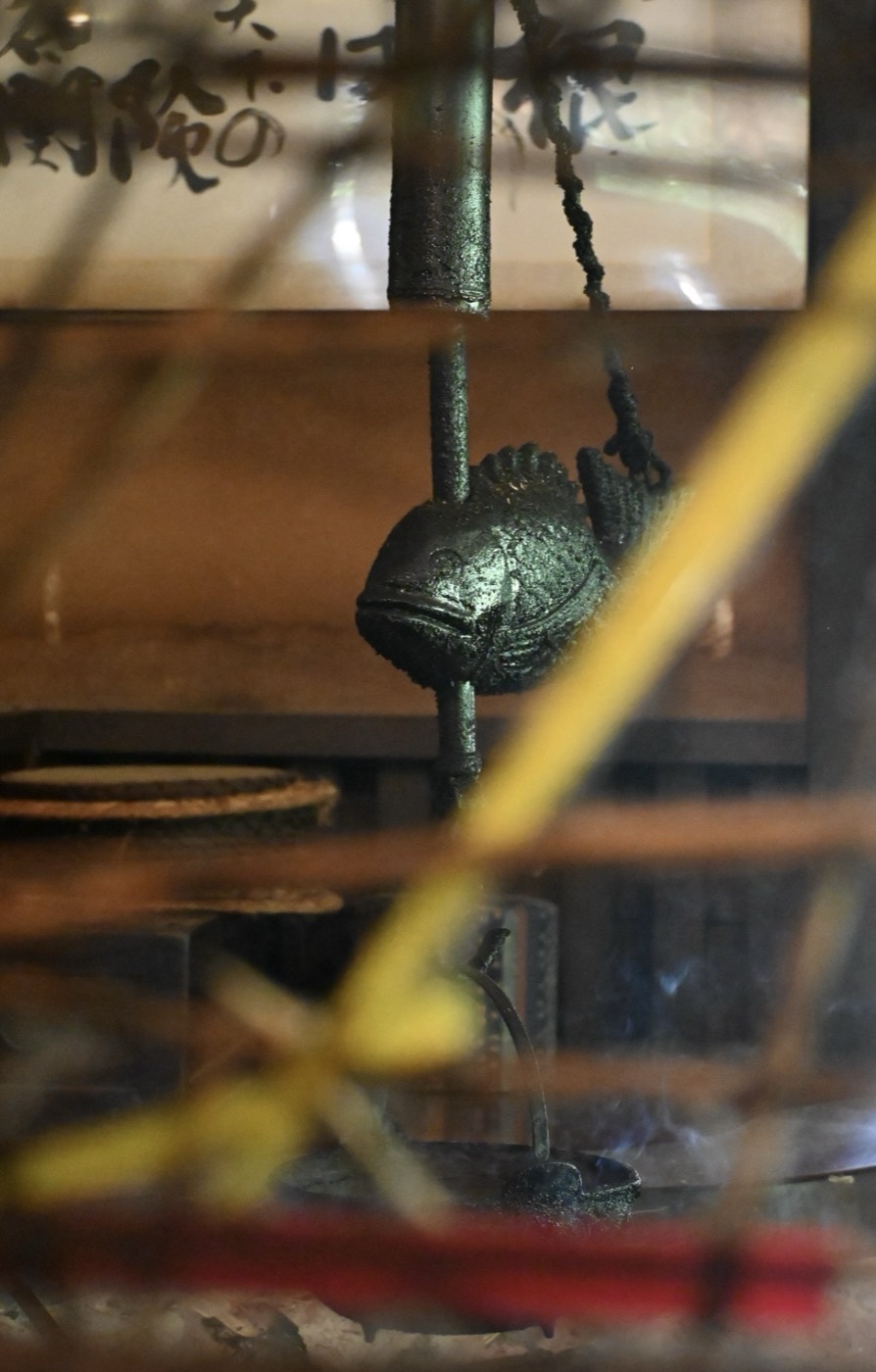 Photograph of a cast-iron fish above a smoking hearth