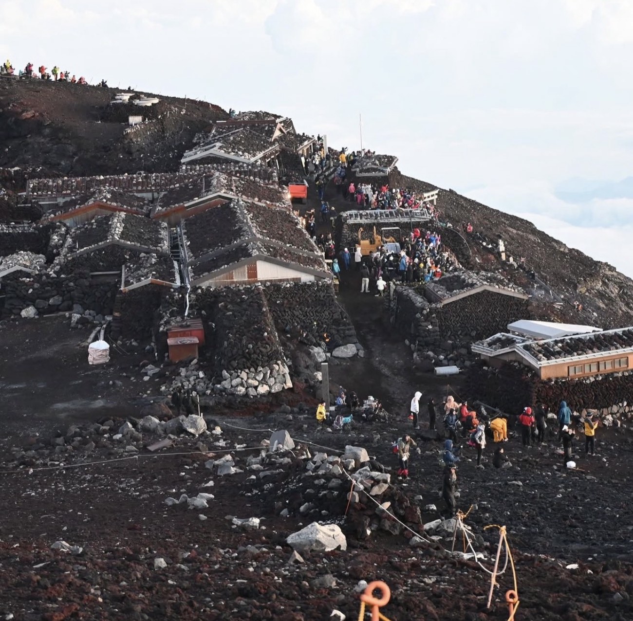 Photograph of climbers among stone huts near the summit of Mount Fuji