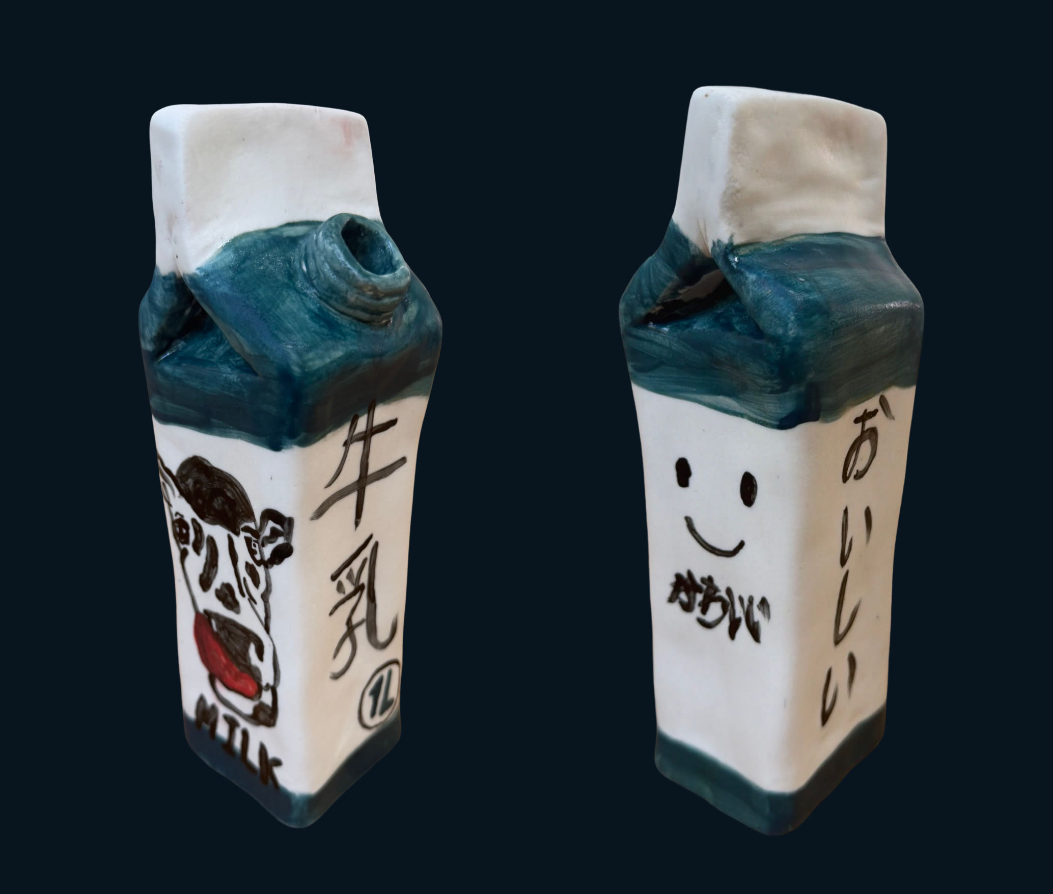 Two ceramic milk cartons side by side, one with a smiling face and Japanese writing, one painted with a dalmatian cow