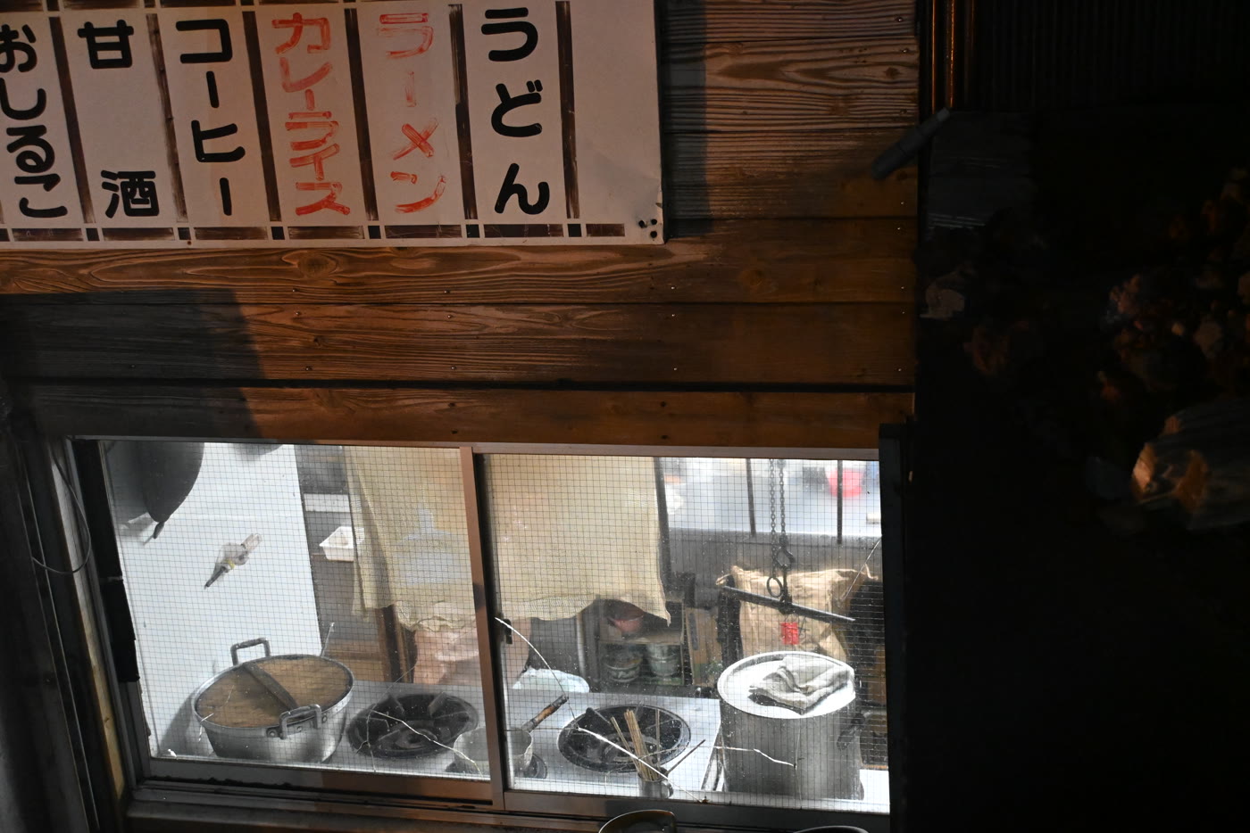 Noodle stand window and hand-painted menu signs at night