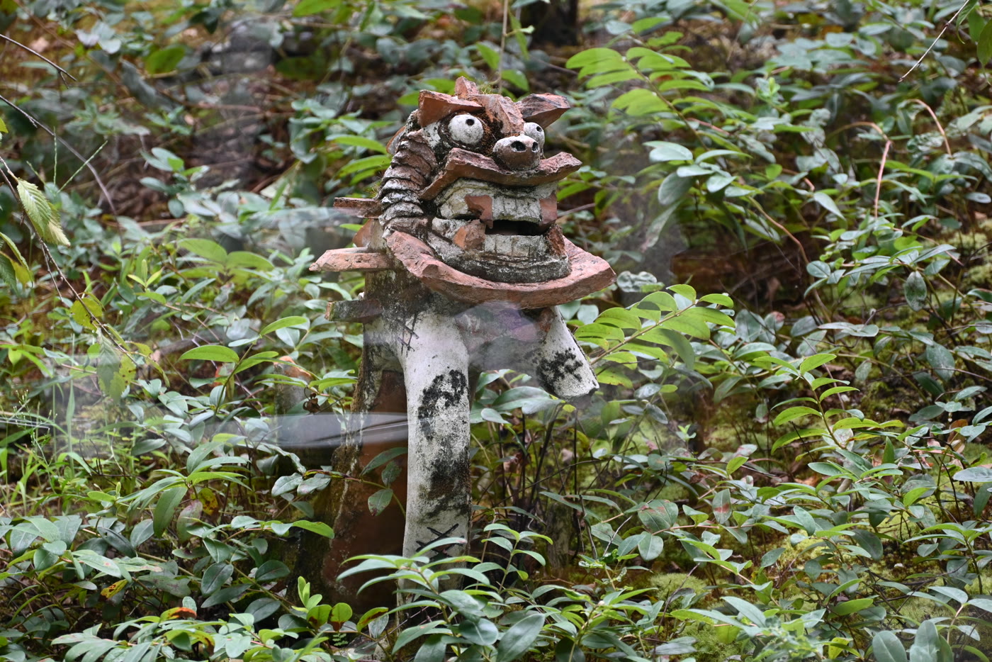 Ceramic lion among green leaves, seen through a window